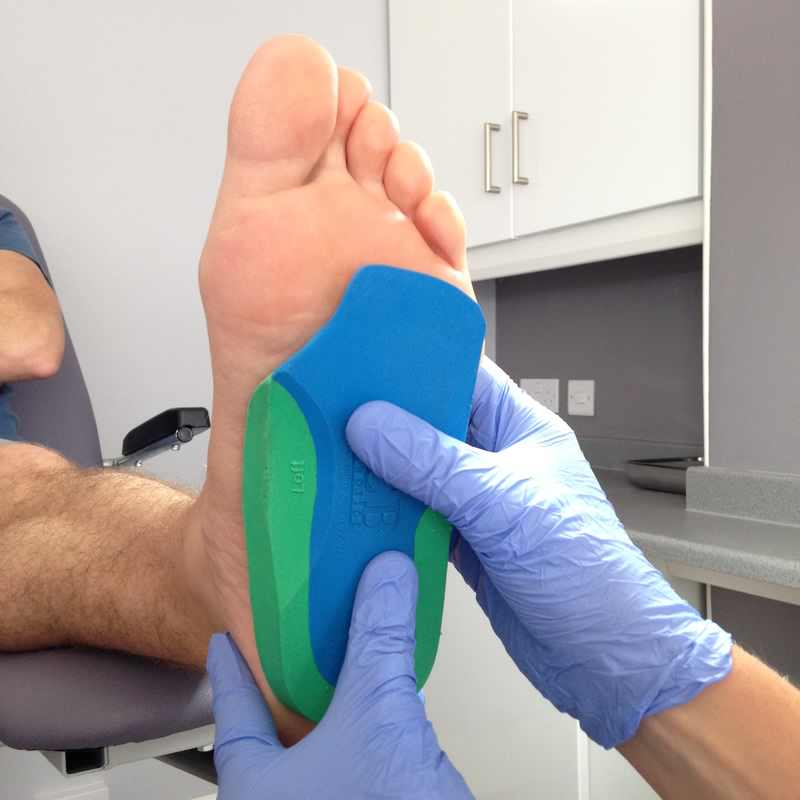 Sidmouth Podiatrist holding orthotic insole to the plantar surface of the foot